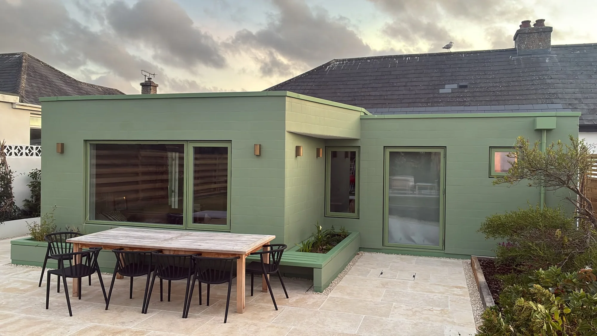 Completed green bungalow extension with paved terrace in Cornwall